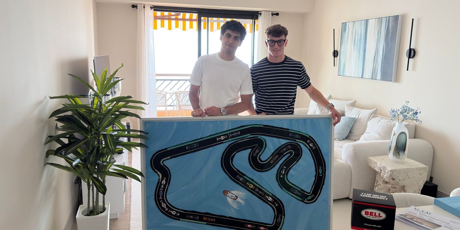 Gabriel Bortoleto et Jules Vincent tiennent le tableau du circuit d'Interlagos, dans un salon.