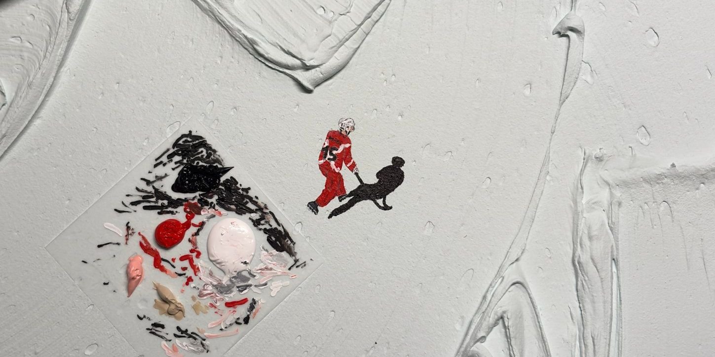 Un joueur de hockey en maillot rouge peint en miniature sur la matière blanche, à côté de la palette.